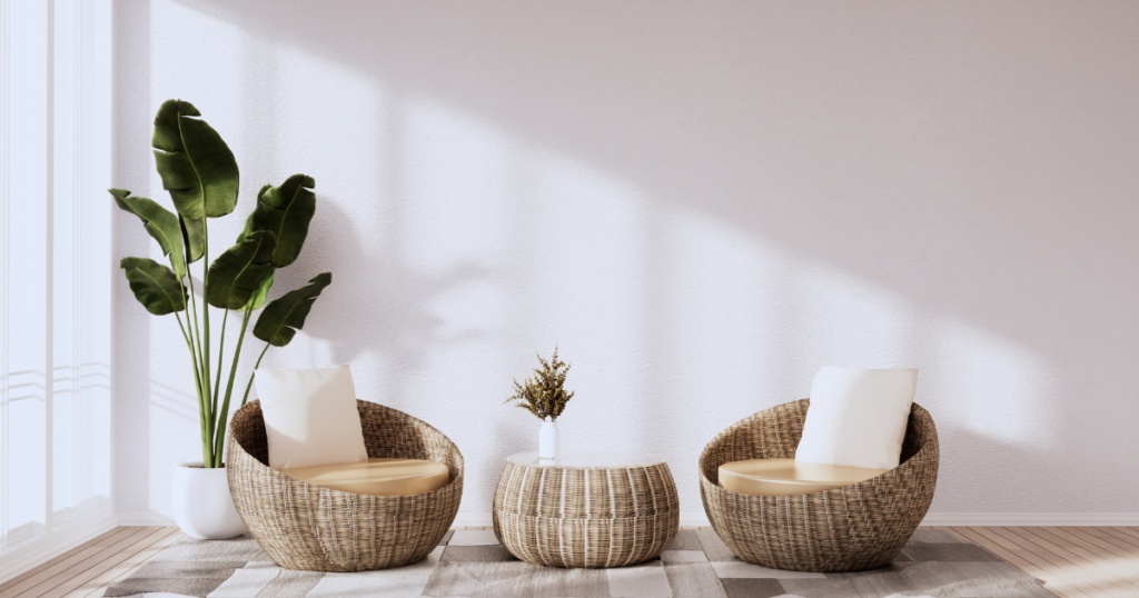 Modern minimalist living room with wicker armchairs, round table, potted plant, and rug.