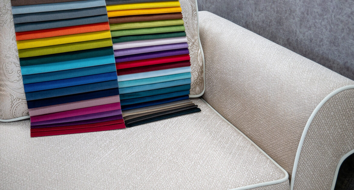 A selection of vibrant fabric swatches in various colors displayed on a textured beige sofa, showcasing a wide range of upholstery options