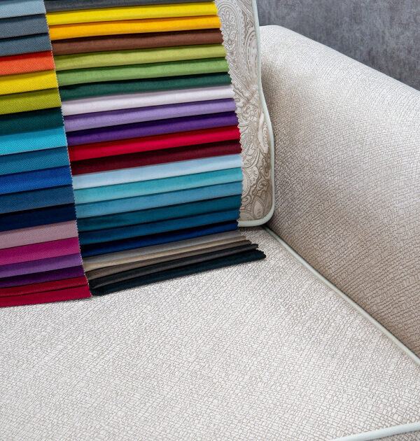 A selection of vibrant fabric swatches in various colors displayed on a textured beige sofa, showcasing a wide range of upholstery options