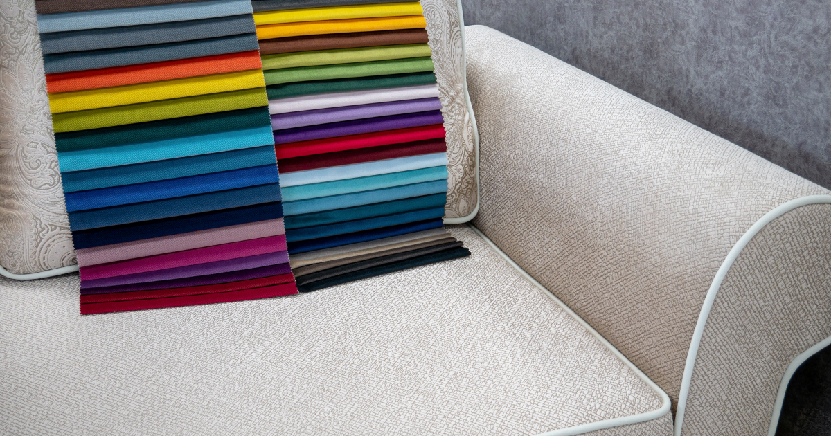 A selection of vibrant fabric swatches in various colors displayed on a textured beige sofa, showcasing a wide range of upholstery options